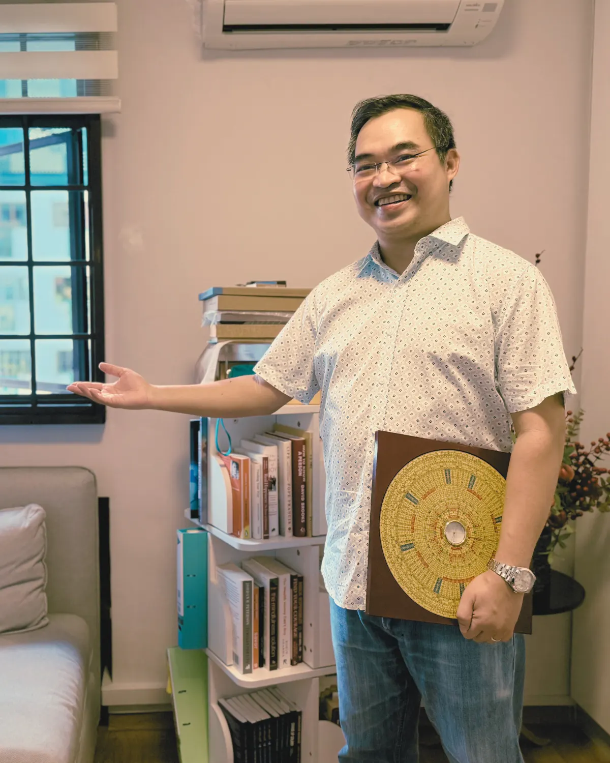 Thanapark welcoming a client into a Singapore home, luopan compass in hand