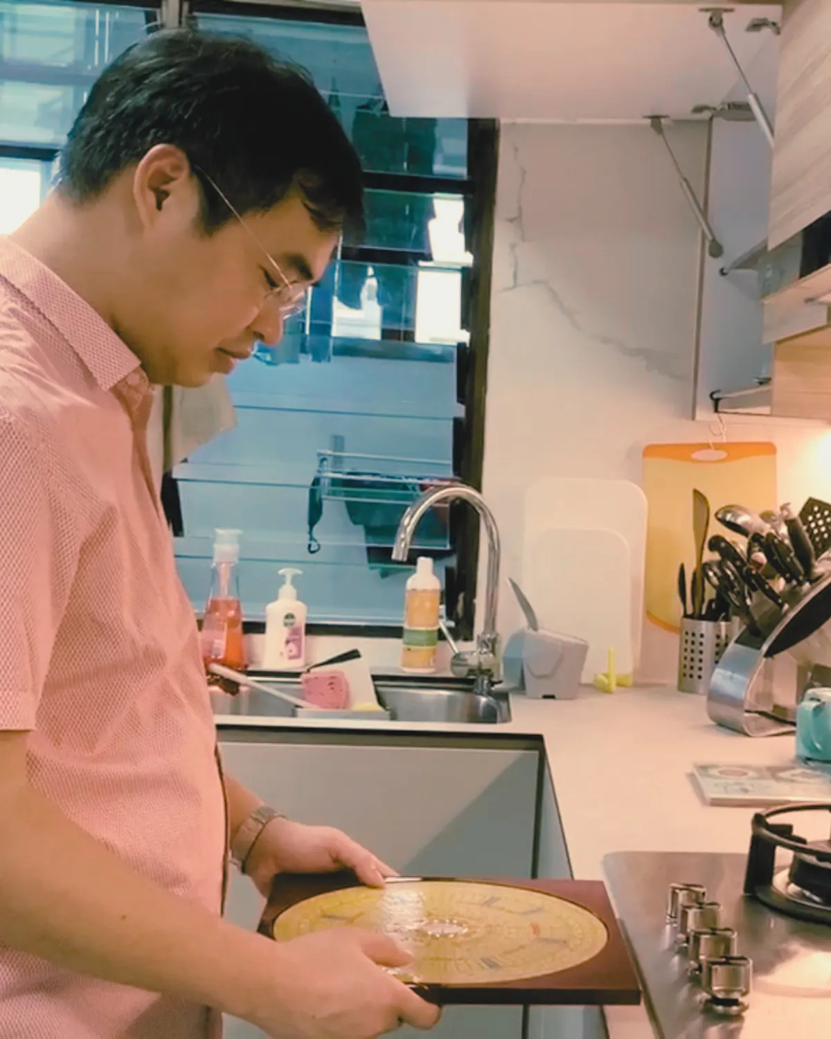 Thanapark taking a luopan reading at the kitchen stove during a home assessment