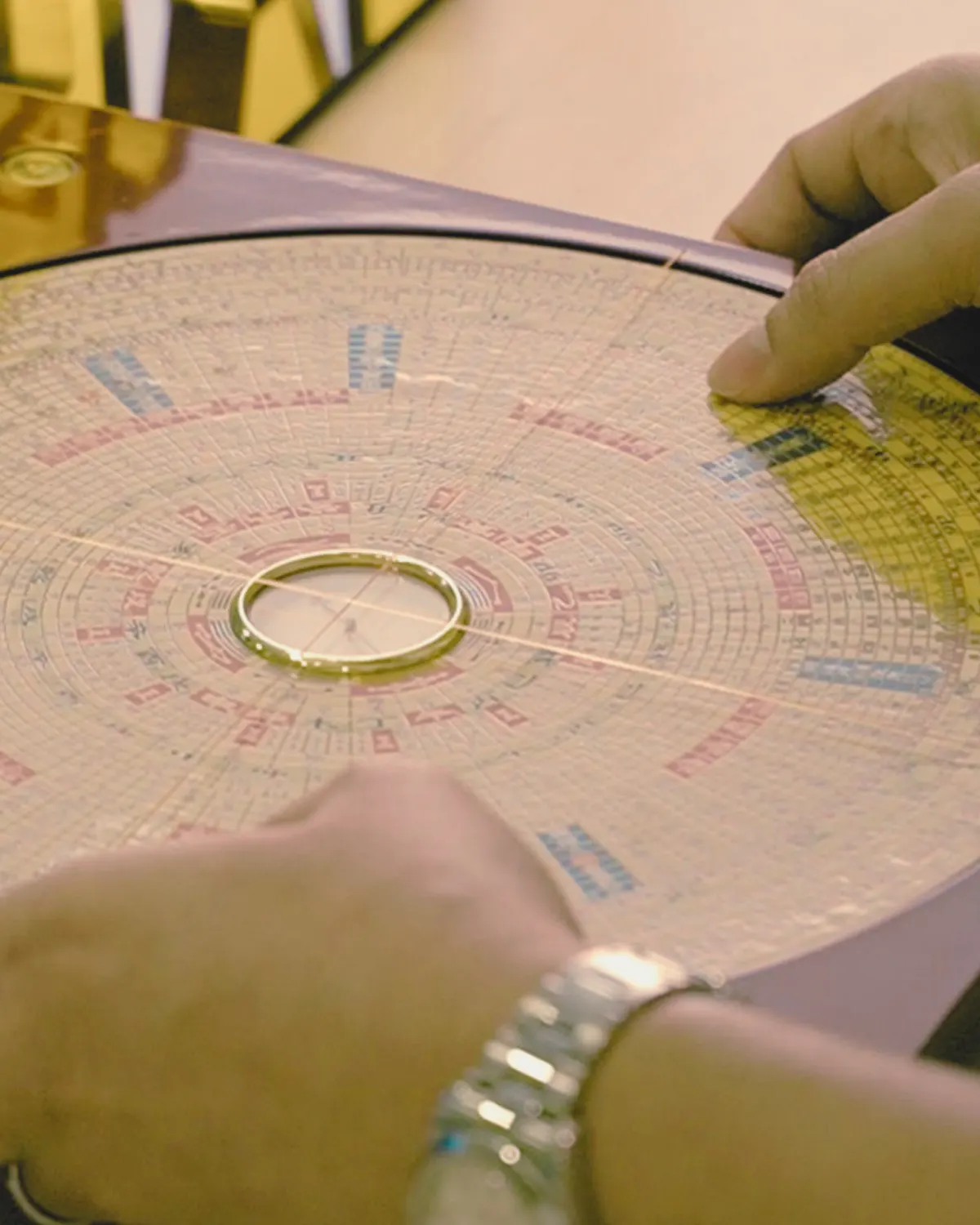 Close-up of hands aligning a luopan compass during a Feng Shui reading